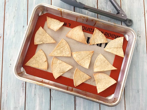 Baked chips cooling on a baking mat lined pan.