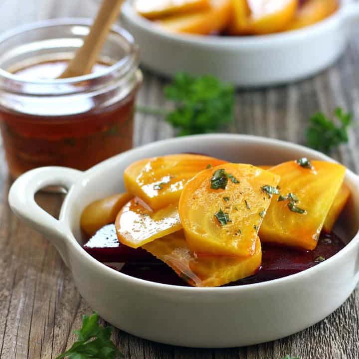 Baked red and yellow beets in white dishes.