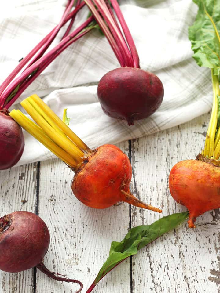 Raw red and yellow beets with greens.