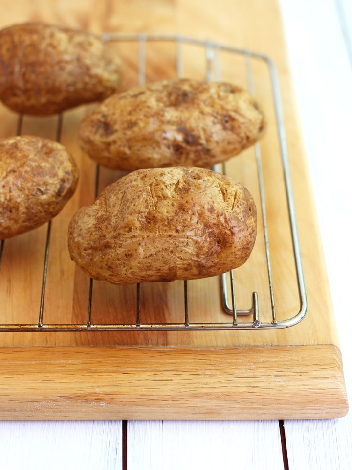Golden baked potatoes on a cooking rack.