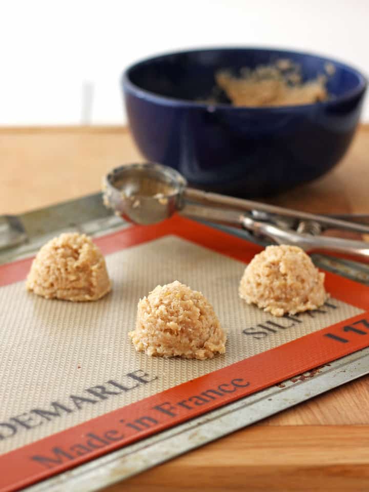 Macaroon dough scooped onto a silicone baking mat.