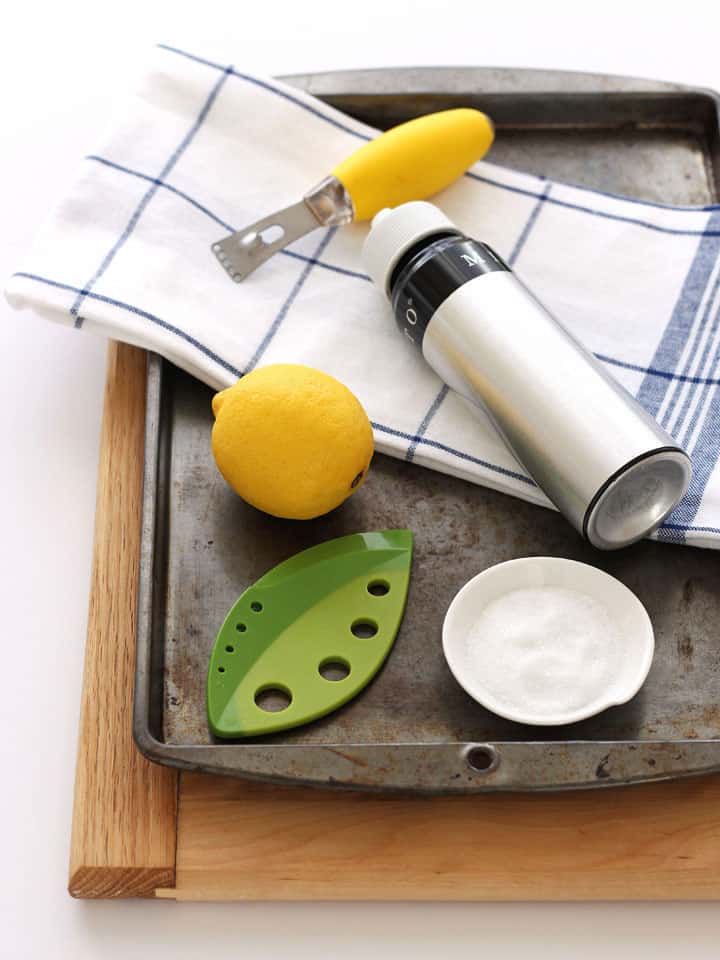 Sheet pan with oil sprayer, lemon, zester, and salt.