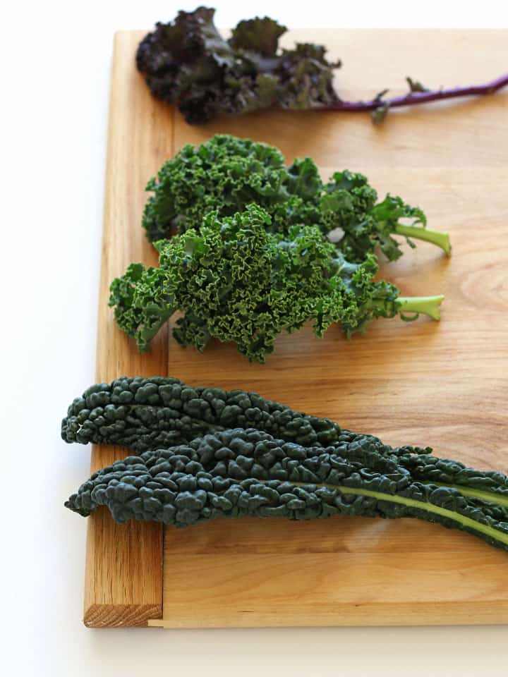 Three varieties of kale on a cutting board.