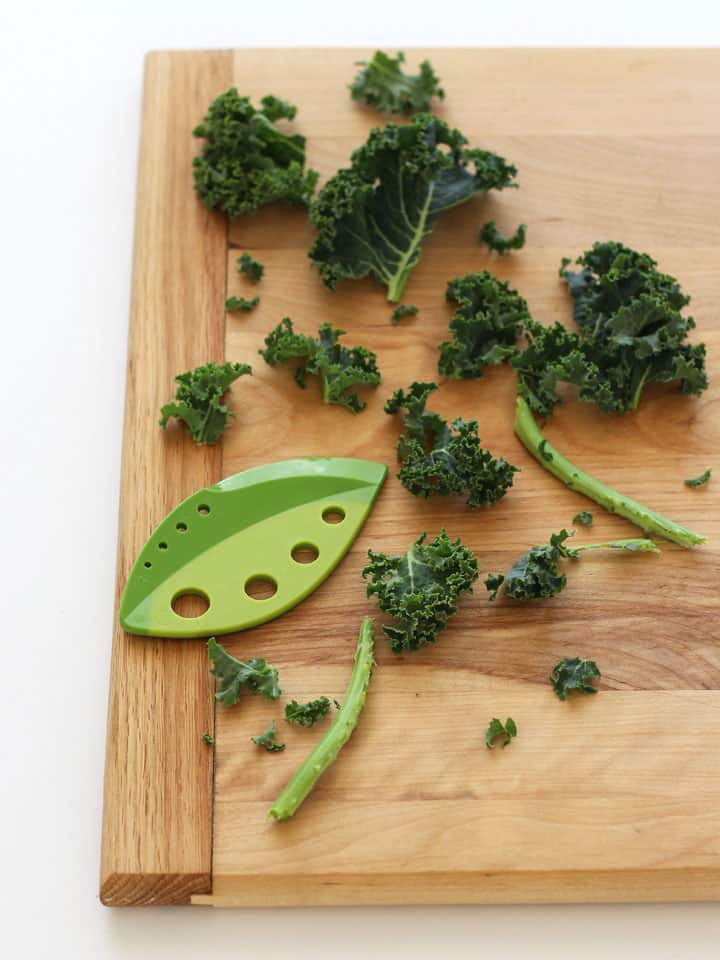 Curly kale leaves and stems on a cutting board.
