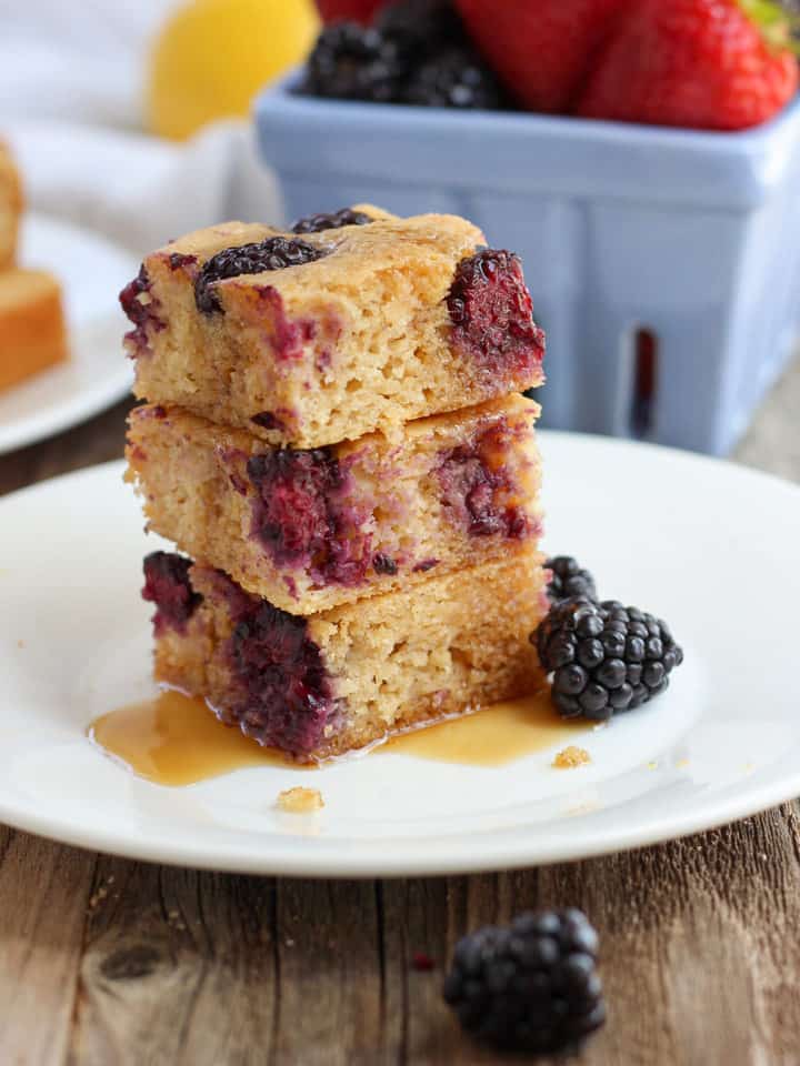A stack of pancake squares dripping with maple syrup on a white plate.