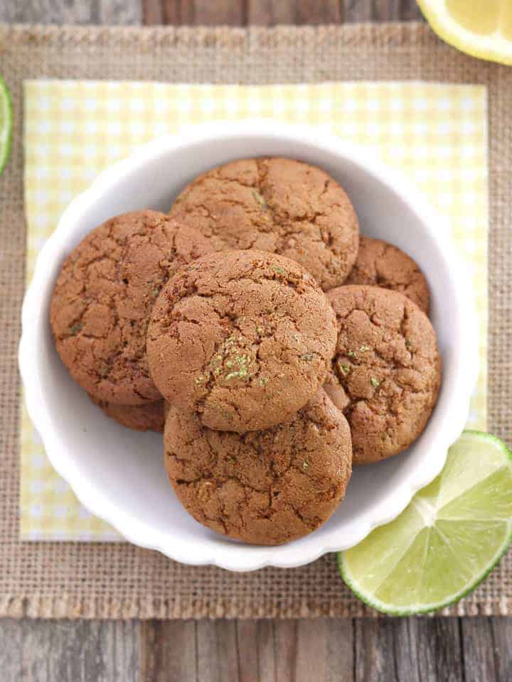 Small white bowl filled with small cookies next to a lime wedge.