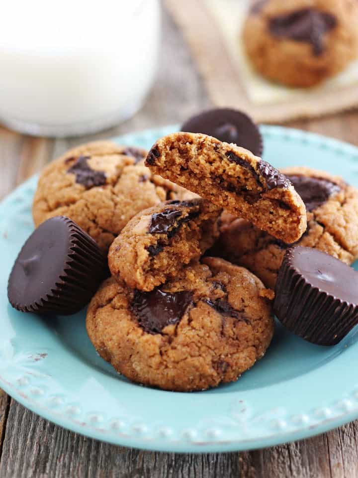 Peanut butter cookie broken in half showing melty peanut butter cup inside.