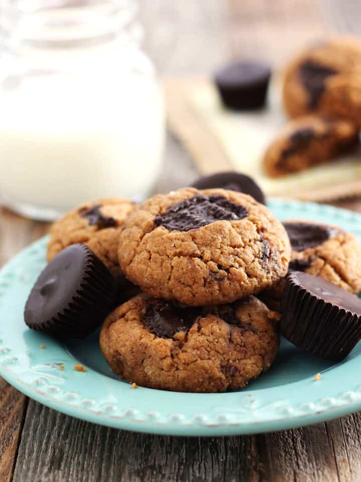 Small batch of peanut butter cookies piled on a blue plate next to a glass of milk.