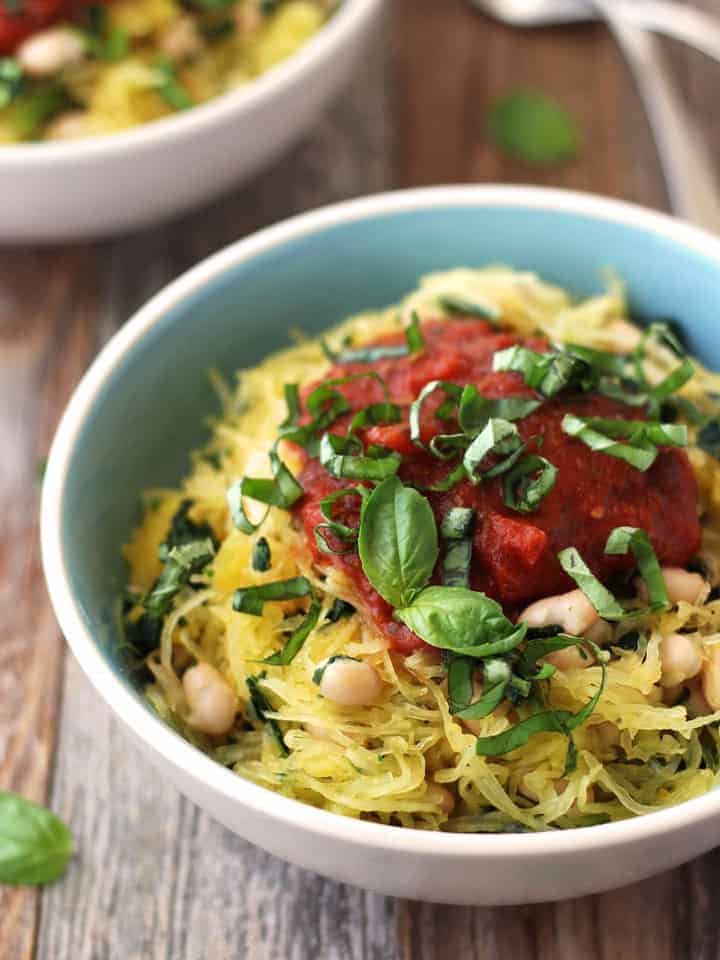 Spaghetti squash in a bowl with beans, tomato sauce, and fresh basil.