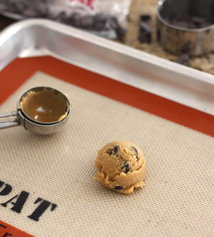 Scoop of cookie dough on a sheet pan lined with a silicone mat.