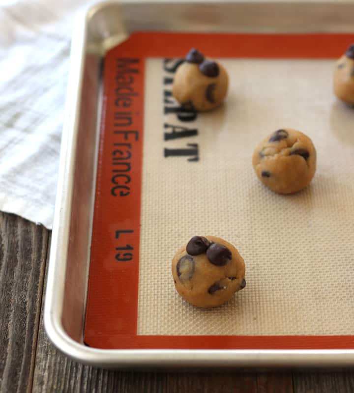 Cookie dough balls spread out on a sheet pan.