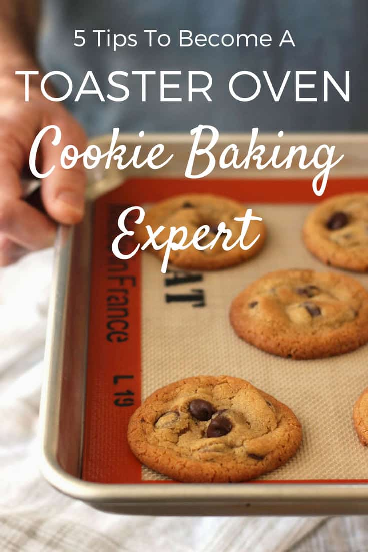 Person holding baked cookies on sheet pan.