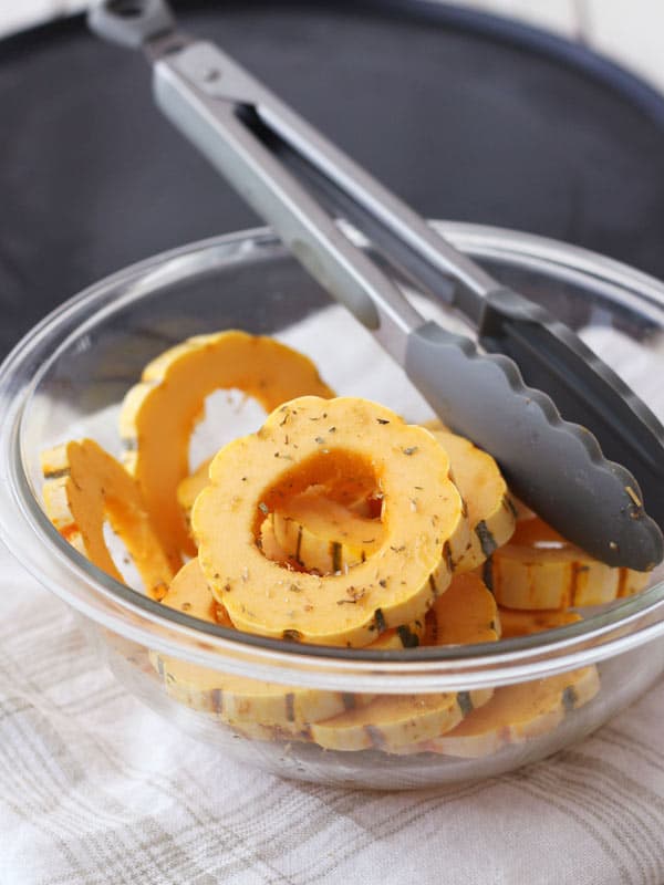 Seasoned slices of delicata squash in a bowl