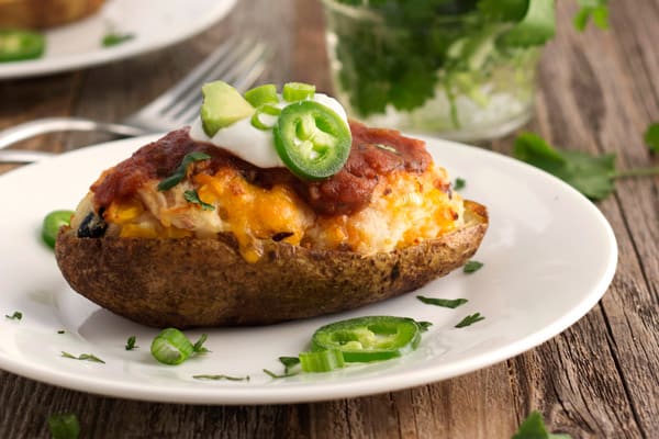 Side view of a twice baked potato with golden melted cheese.