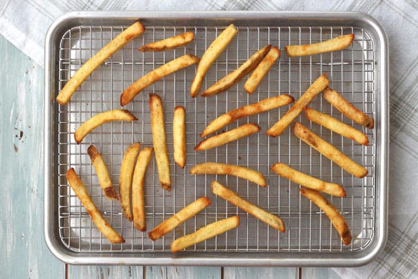 Golden baked fries on a rack inside a sheet pan.
