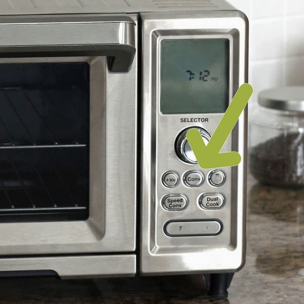 Arrow pointing to convection button on a toaster oven.