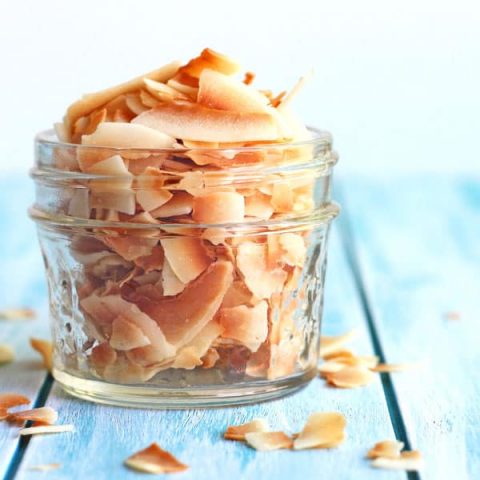 Toasted coconut flakes in a small glass mason jar.