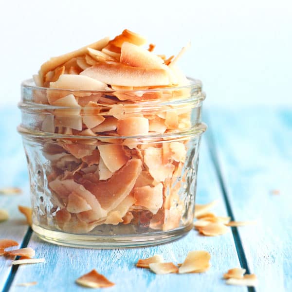 Toasted coconut flakes in a small glass mason jar.