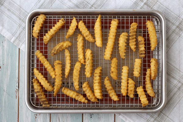 Overhead view of seasoned crinkle fries on a baking sheet.