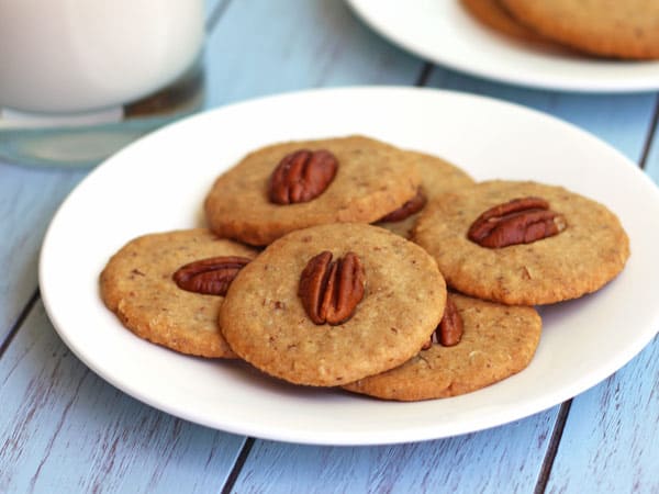 A white plate with pecan cookies on a blue table.