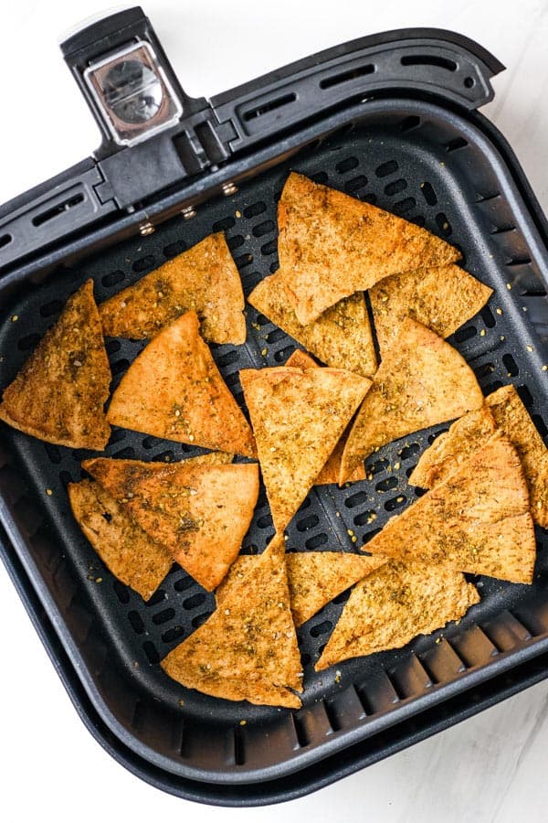 Golden toasted pita chips in an air fryer basket.