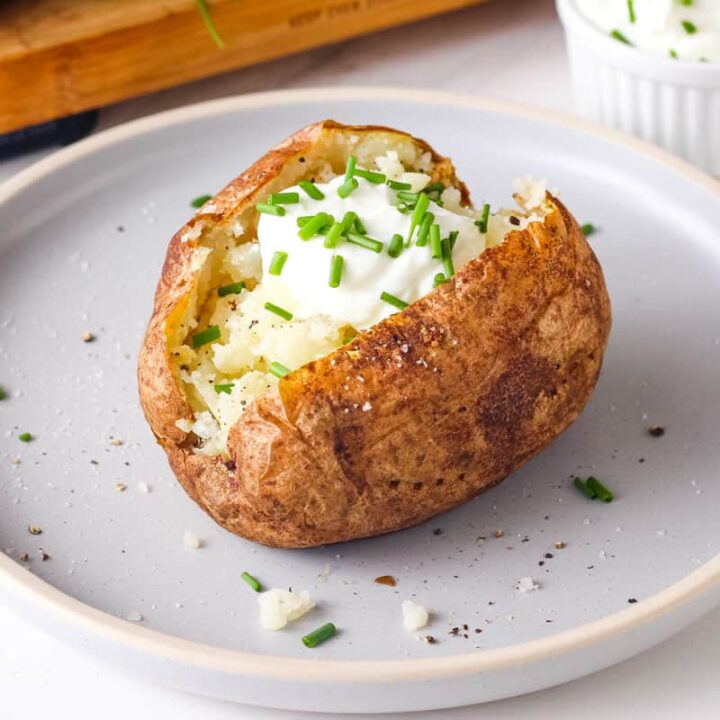 Baked potato topped with Greek yogurt and fresh chives.