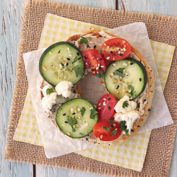 Toasted everything bagel with hummus, cucumbers and cauliflower.