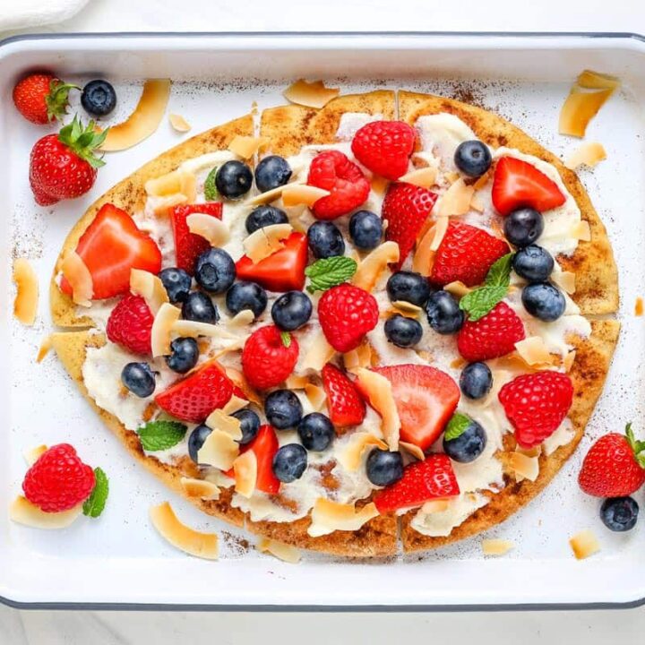Baking tray with berry topped flatbread pizza.