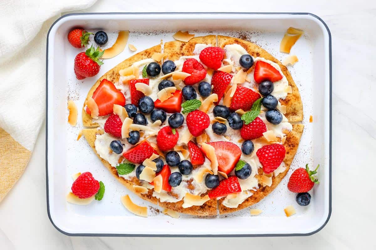 Baking tray with berry topped flatbread pizza.