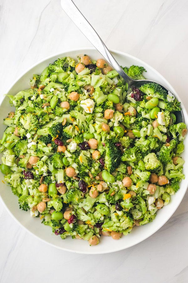 Overhead view of a big bowl of broccoli salad with a large serving spoon sticking out.
