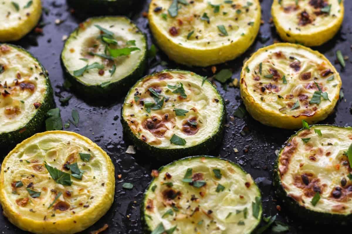 Closeup of cooked zucchini rounds on roasting pan.