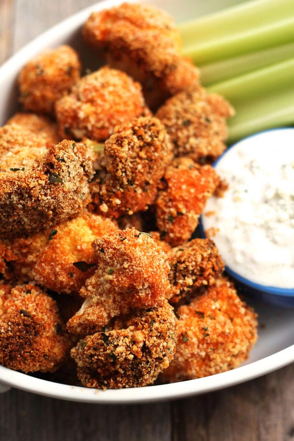 Crispy veggie bites in a white serving bowl with celery and dip.