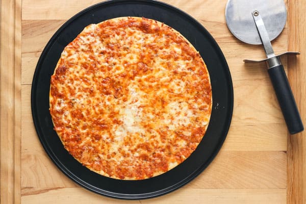 Overhead view of baked pizza on pan with pizza cutter.
