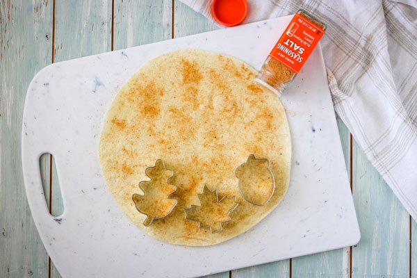 Tortilla on a cutting board with seasoning and cookie cutters.