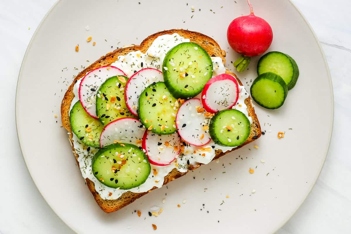 Toasted bread topped with cottages cheese, sliced cucumber, and radishes.