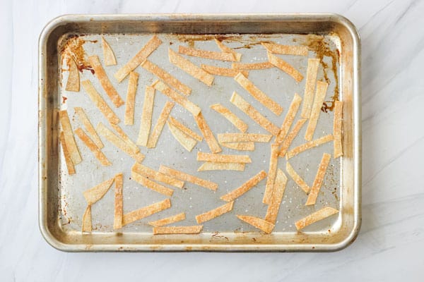 Lightly browned tortilla strips on a sheet pan.