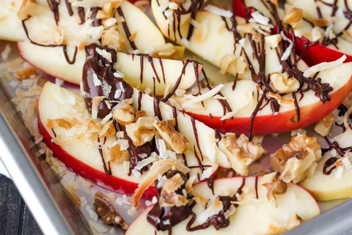 Apple slices drizzled with chocolate and topped with nuts and toasted coconut.