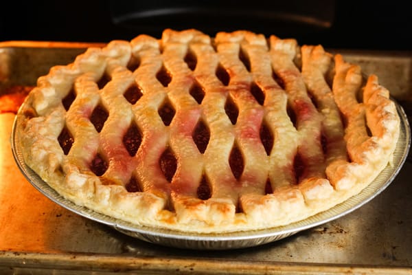 Pie baking inside toaster oven with crust barely browned on edges.