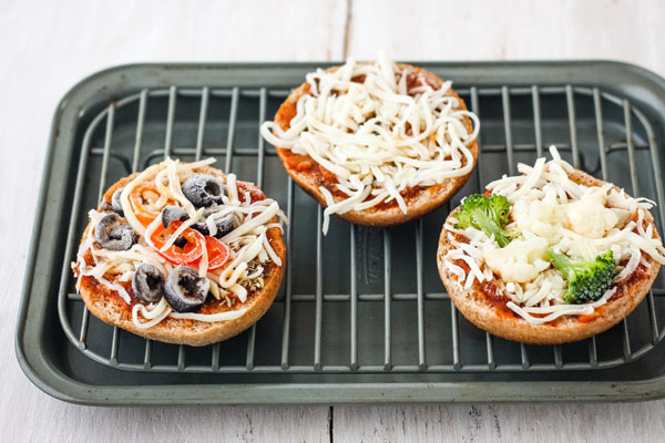 Frozen pizza bagels on a small cooking rack inside a small baking pan.