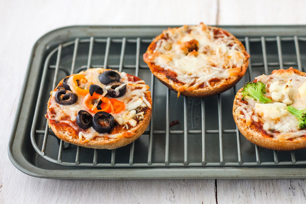 Cooked pizza bagels on a toaster oven rack and pan.