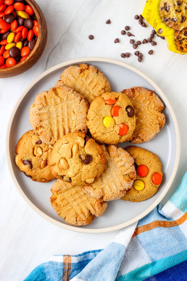 Plate of cookies with an open bag of chocolate chips and a bowl of Reese's Pieces.