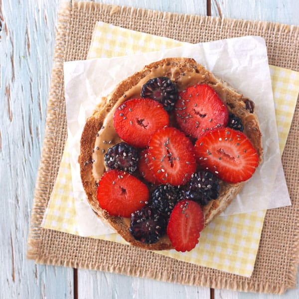 A whole grain bagel topped with peanut butter, fresh berries and chia seeds.