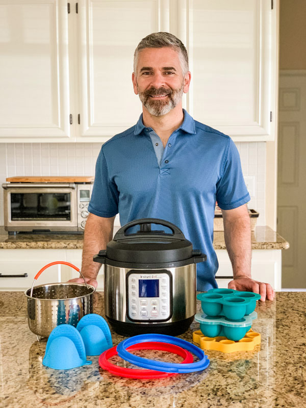 Man standing in a kitchen with a 3-Quart Instant Pot surrounded by accessories.