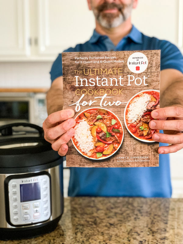 Hands holding the Ultimate Instant Pot Cookbook For Two.