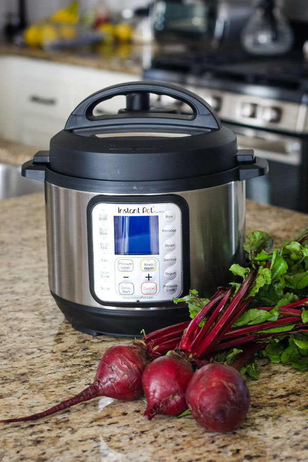Instant Pot Mini Duo Plus on a kitchen counter with a bunch of fresh beets.