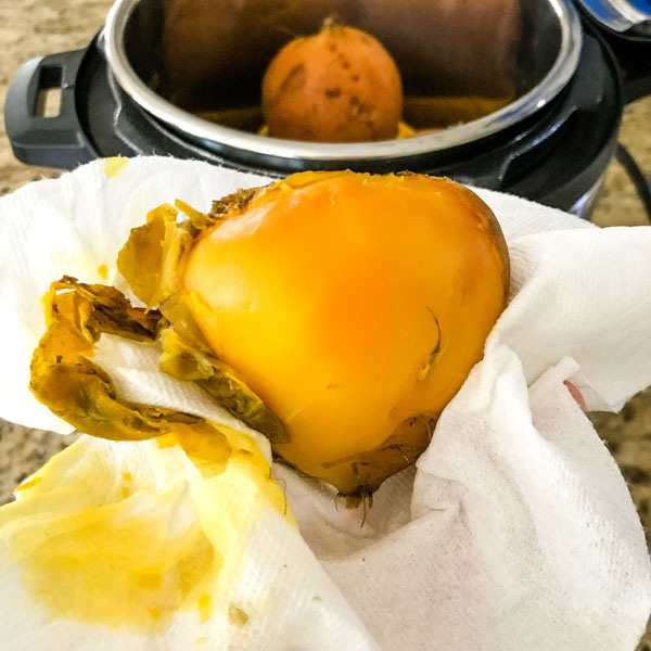 Cooked golden beet in a paper towel with skin rubbed off.