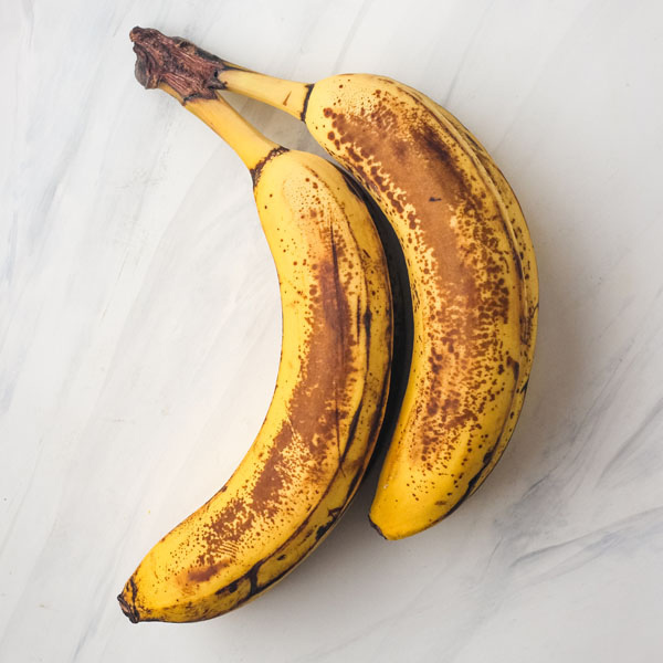 Overripe browned bananas on a white table.
