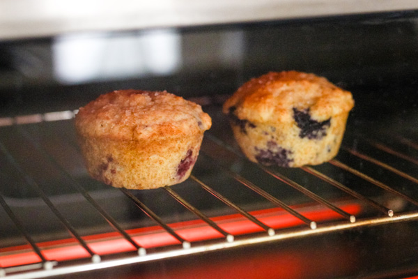 Muffins on a baking rack inside a countertop oven.