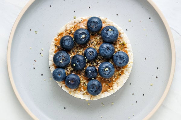 Rice cake with peanut butter, blueberries, and hemp hearts.