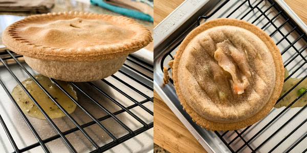 Pot pie leaking sauce on a black rack in a silver pan